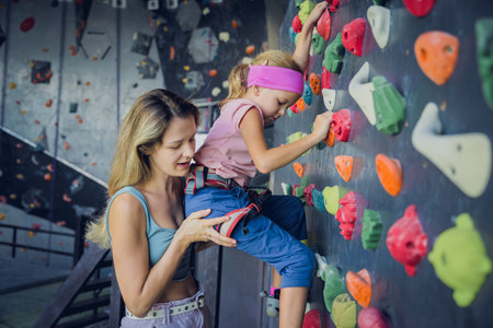 A strong baby climber climbs an artificial wall with colorful grips and ropes.の写真素材