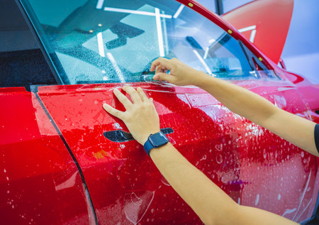 The process of installing protective film on the new red car.の写真素材
