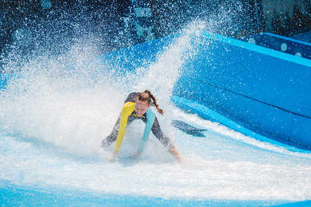 Beautiful young woman surfing on a wave simulator at a water amusement park