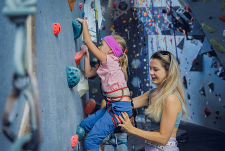 A strong baby climber climbs an artificial wall with colorful grips and ropes.の写真素材