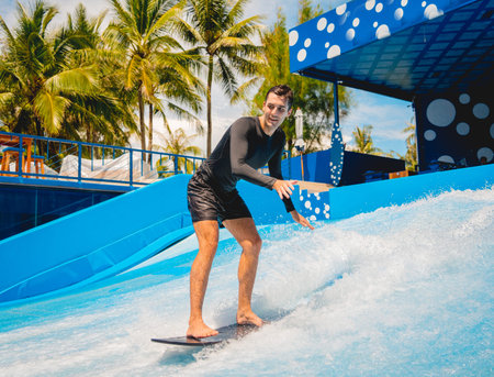 Young man surfing on a wave simulator at a water amusement park