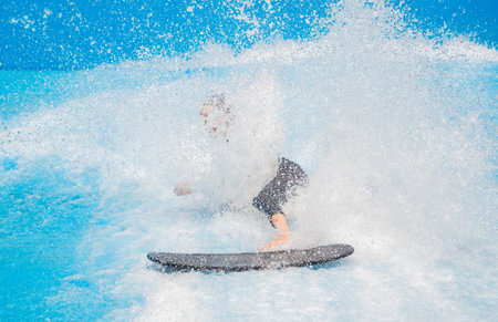 Beautiful young woman surfing on a wave simulator at a water amusement parkの写真素材