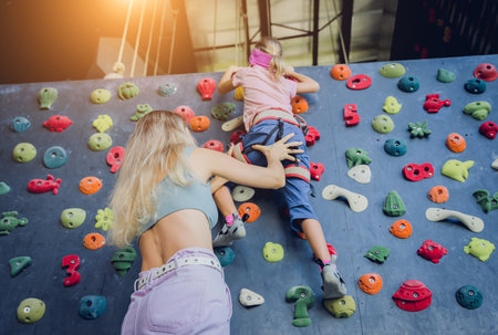 A strong baby climber climbs an artificial wall with colorful grips and ropes.の写真素材