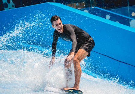 Young man surfing on a wave simulator at a water amusement parkの写真素材