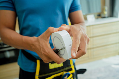 A technician installs a security alarm siren in a modern apartment.