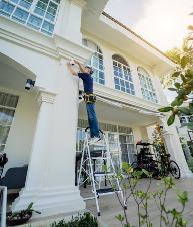 A technician installs a CCTV camera on the facade of a residential building.の写真素材
