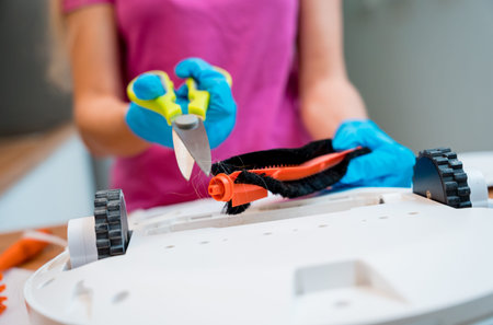 A young woman cleans a robot vacuum cleaner from dirt after cleaning.