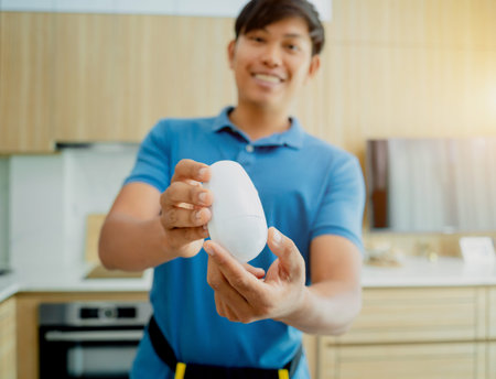 A technician installing motion sensor detector in a modern apartment.