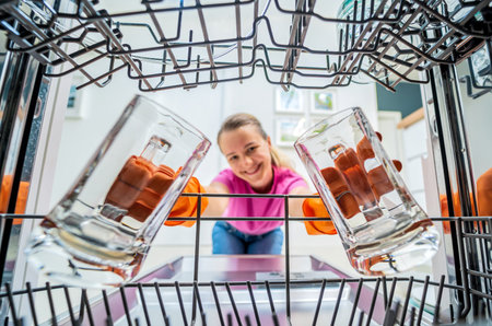 Young woman takes dishes out of the dishwasher machine