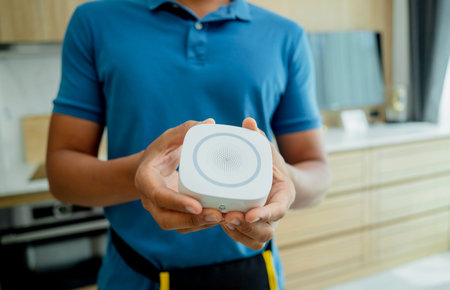 A technician installs a security alarm siren in a modern apartment.
