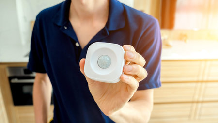 A technician installs a modern movement detector in a cozy apartment