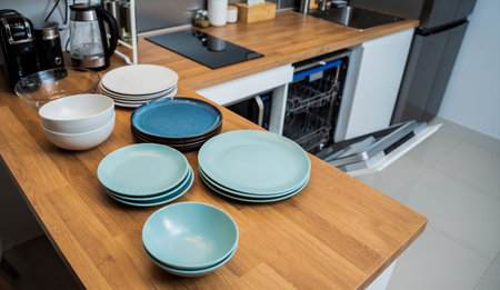 The white kitchen and opened dishwasher with clean dishes