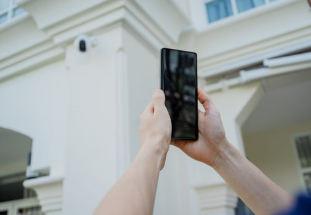 A technician sets up a CCTV camera on the facade of a residential building.