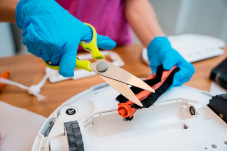 A young woman cleans a robot vacuum cleaner from dirt after cleaning.