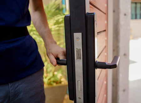 A technician installs a modern smart door lock on the wood door