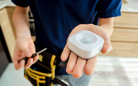 A technician installs a modern movement detector in a cozy apartment