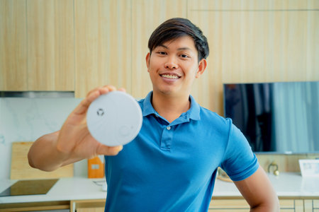 Technician installing fire safety detector in a modern apartment