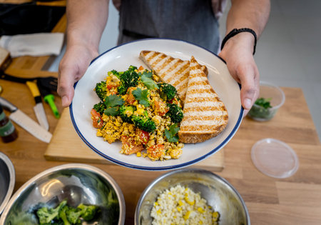 Chef at the kitchen preparing tofu scramble with vegetables