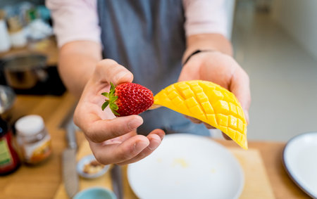 Chef at the kitchen preparing bowl of oats with strawberries and mangoの写真素材