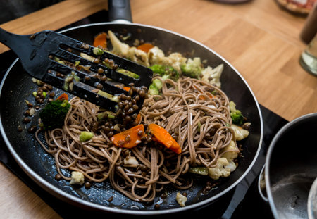 Chef at the kitchen preparing japanese buckwheat pasta with lentils