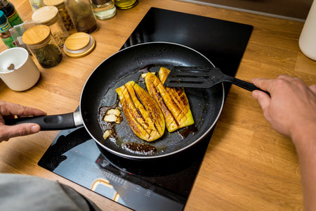 Chef at the kitchen preparing grilled eggplants with garlicの写真素材