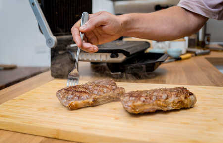 Chef at the kitchen preparing beef steaks on the home electric grillの写真素材