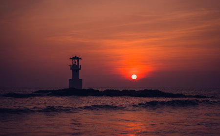 A lighthouse in the ocean during a beautiful sunsetの写真素材