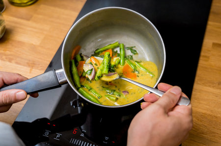 Chef at the kitchen preparing green curry with herbs and riceの写真素材
