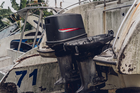 Old and rusty motor boats on a landfill surrounded by tropical forest
