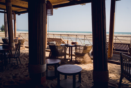 A cozy beach cafe with couch and rustic chairsの写真素材