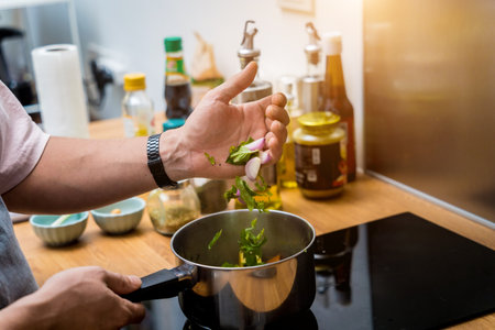 Chef at the kitchen preparing green curry with herbs and riceの写真素材