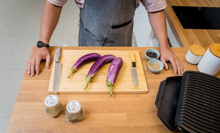Chef at the kitchen preparing grilled eggplants with garlicの写真素材