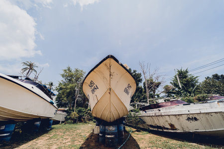 Old and rusty motor boats on a landfill surrounded by tropical forestの写真素材
