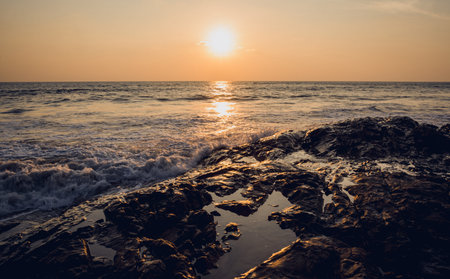 A large rocks surrounded by waves of the ocean