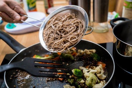Chef at the kitchen preparing japanese buckwheat pasta with lentilsの写真素材