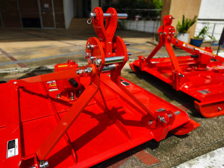 Red large excavators are stationed in a green field in front of a building