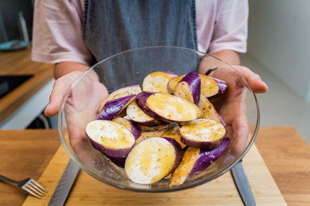 Chef at the kitchen preparing grilled eggplants with garlicの写真素材