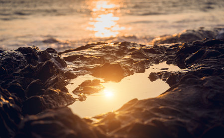 A large rocks surrounded by waves of the oceanの写真素材