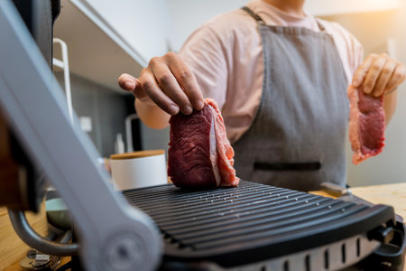 Chef at the kitchen preparing beef steaks on the home electric grillの写真素材