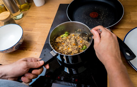 Chef at the kitchen preparing healthy quinoa bowl with avocado
