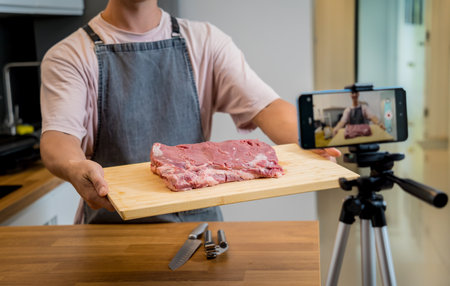 The chef is broadcasting live from workshop how to prepare a beef steaks on the electric grillの写真素材