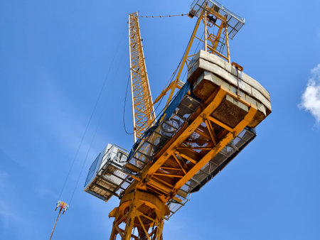 A large yellow crane stands out against a bright blue sky