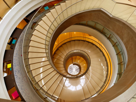 A beautifully designed spiral staircase in a modern building with glass railingの写真素材