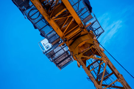A large yellow crane stands out against a bright blue sky