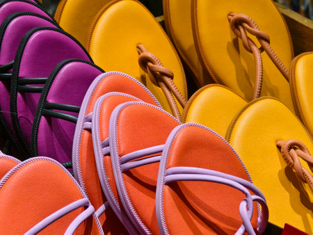 A colorful box filled with a variety of purple and orange flip flopsの写真素材