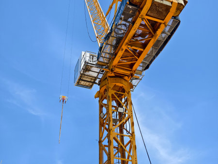 A large yellow crane stands out against a bright blue sky