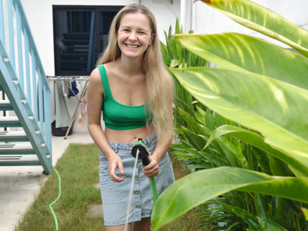 A young woman waters her beautiful garden