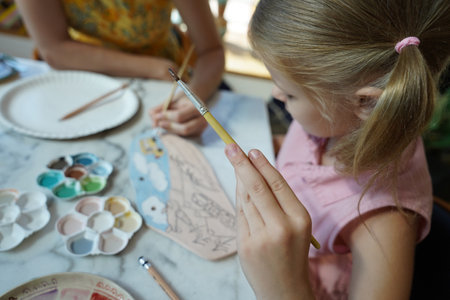 A young mother and her daughter enjoy a creative art session at homeの写真素材