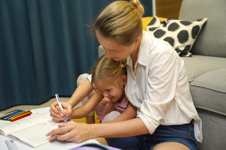 A mother supports her daughter with homeworkの写真素材