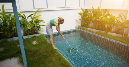 A young woman clean leaves out of a pool